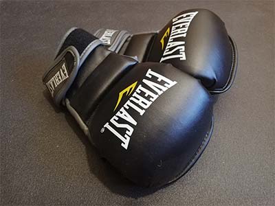 A pair of black MMA gloves lying on the gym mat.