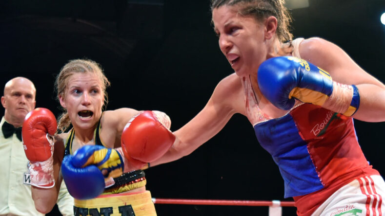Two female boxers exchange punches in the boxing ring.