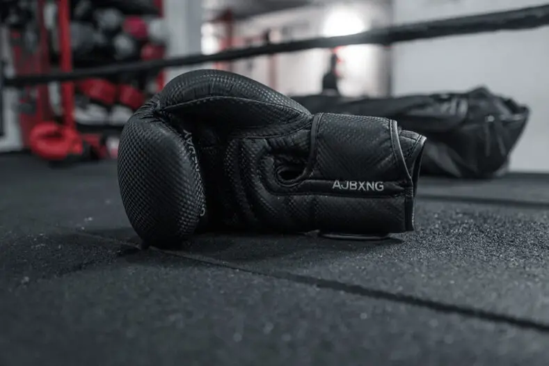 Two black boxing gloves lying on the canvas.