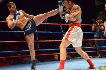 A kickboxer land a high kick in fight.