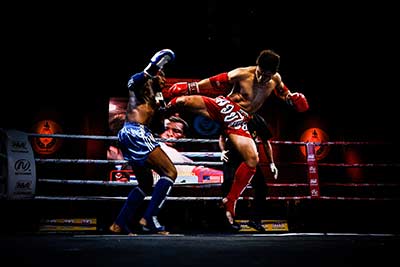 One Muay Thai fighter lands a body kick during his fight.