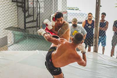 Two MMA fighter competing inside the cage wearing shin guards.