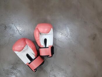 Two red and white boxing gloves on ground.