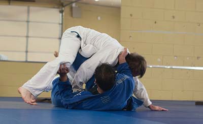 Two BJJ players on the ground grappling for position.