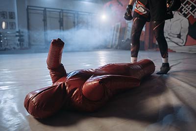 An MMA fighter uses a grappling dummy during his training session in the gym.