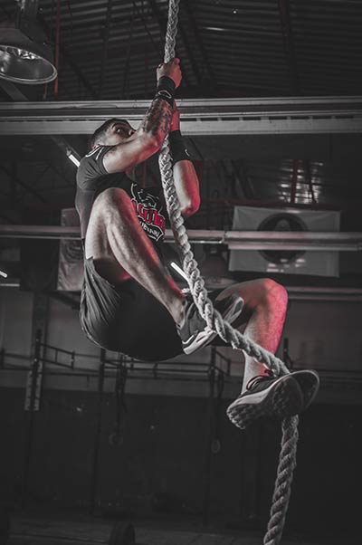 A student in the MMA training doing a rope climb.