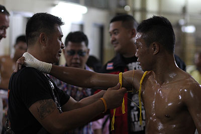 A Muay Thai fighter wearing a Praciat prepares with his master before his fight.