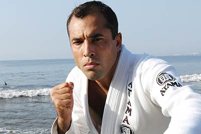 Royce Gracie poses on a beach in Brazil wearing his BJJ Gi.