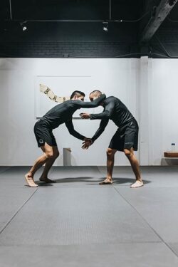 Two MMA fighters grappling for dominance in the gym.