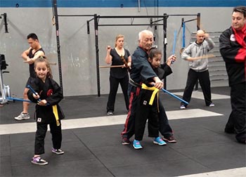 An elderly Arnis master working with a young student.