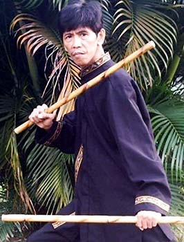 A master poses using baston sticks in a jungle.