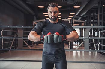 A boxer poses in the gym wearing boxing gloves.
