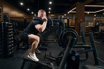 A man doing leg squats with heavy weights in the gym.