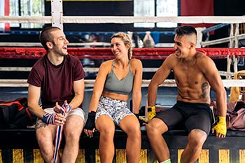 Three people sitting on the boxing ring after training.