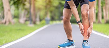 A man holds his leg while out running after suffering an injury.
