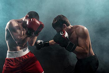 Two professional boxers boxing on black smoky background.