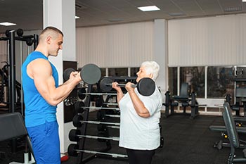 A personal trainer works with an elderly client.