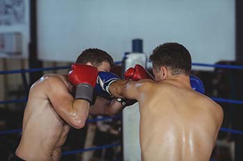 Two boxers compete in the boxing ring and throw punches.