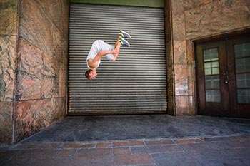 A parkour athlete doing a front flip in the street.