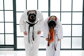 A female teacher and student bow in the dojo.