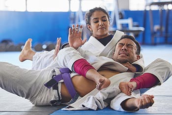 A Brazilian Jiu-Jitsu student makes a purple belt tap to a choke.