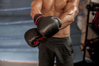 A man putting on some boxing gloves in the ring.