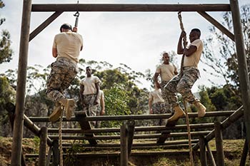 A group of military soldiers train in rope climbing.