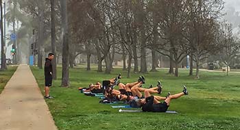 The navy with a military fitness trainer working out on a foggy morning in park.