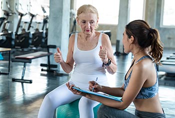 A personal trainer with a senior client in the gymnasium.