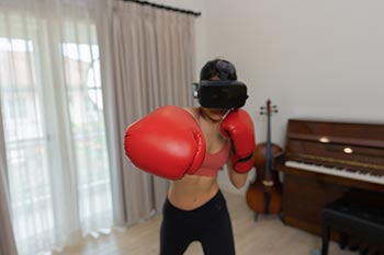 A young woman works out using VR boxing headset and VR gloves.